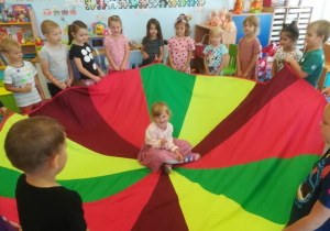 „Karuzela” - zabawa z chustą animacyjną – jubilatka siedzi pośrodku pozostałe dzieci kręcą chustą.